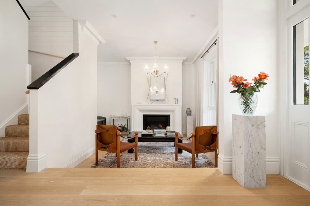 Bright sitting room with a fireplace, leather chairs and flowers at Eltham House